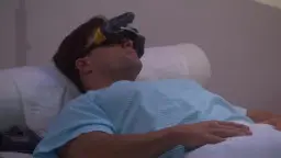 Junger Mann mit VR-Brille liegt entspannt auf weißem Kissen und träumt