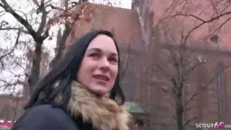 Lena mit schwarzem Haar und Pelzkragen lächelt verführerisch vor Berliner Backsteinkirche